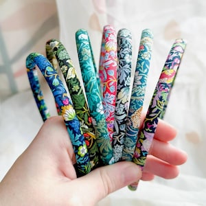 May include: A set of eight colourful floral patterned headbands. The headbands are made of fabric and have a simple design.
