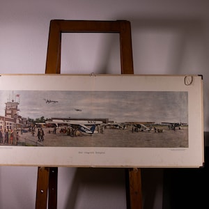 Könnte beinhalten: Ein panoramischer Vintage-Druck mit dem Titel Het vliegveld Schiphol, der eine historische Flughafenszene mit mehreren Propellerflugzeugen auf dem Rollfeld, Bodenpersonal und Passagieren an einem Terminalgebäude in gedeckten Farben zeigt.