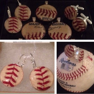 May include: A set of baseball-themed jewellery, including earrings, cufflinks, and a pendant. The jewellery features vintage baseballs with red stitching and a white background. The pendant has the text "Major League Baseball" and "Official" on it.