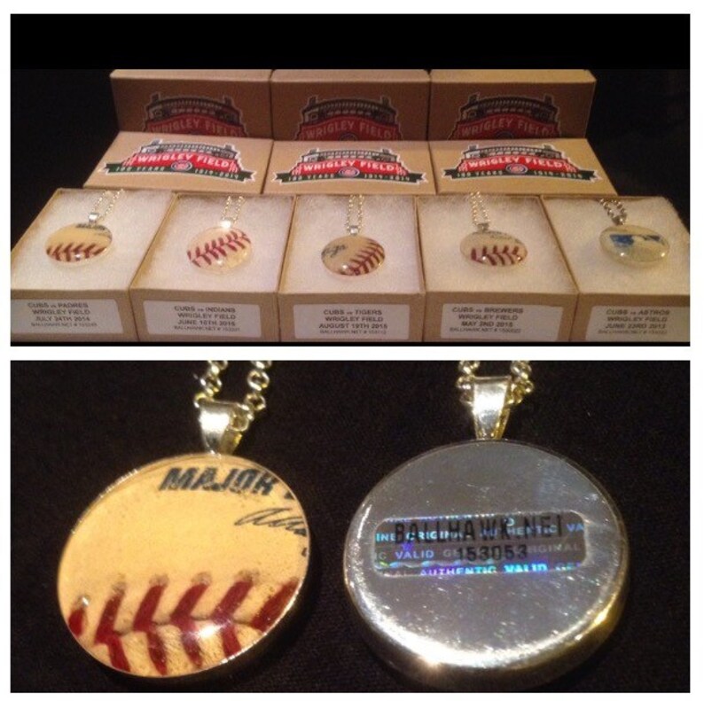 Op de afbeelding: Een close-up van een baseball kettinghanger met een zilveren ketting. De hanger is een transparante harskoepel met een honkbal erin. De honkbal is een vintage honkbal met rode stiksels en een tan lederen buitenkant. De achterkant van de hanger is zilver en heeft een holografische sticker met de tekst "INE CRIGIP IC VALID G6153053 ORIGINAL AUTHENTIC VALID".