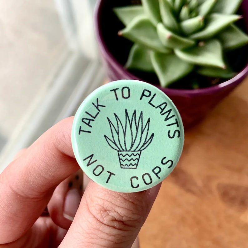 May include: A green button with the text "Talk to Plants Not Cops" and a black line drawing of a potted plant.