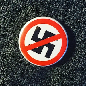 May include: A red circle with a diagonal red line through a black swastika. The circle has a white background.