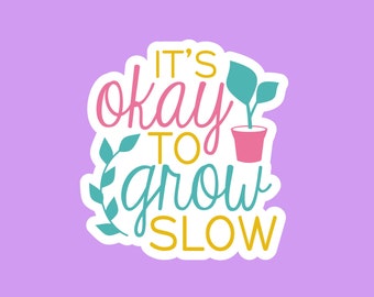 May include: A white sticker with a pink, blue, and yellow design. The sticker says "It's okay to grow slow" with a small potted plant illustration.