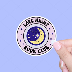 May include: A pink and white sticker with a crescent moon and stars inside. The sticker says "Late Night Book Club" in a retro font.