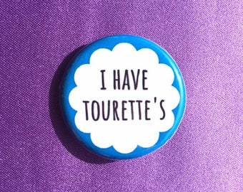 May include: A blue button with a white cloud shape and the text "I HAVE TOURETTE'S" in black.