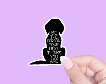 May include: Black silhouette of a dog with the text "Be the person your dog thinks you are" on a light purple background.