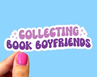 May include: A sticker with a white border and purple text that reads "COLLECTING BOOK BOYFRIENDS" with two small white stars on either side of the text.