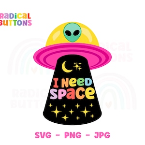 May include: A colorful graphic design of a flying saucer with a green alien inside. The saucer is pink and yellow with a black base that says "I Need Space" in rainbow colors. There are stars and a crescent moon on the black base.