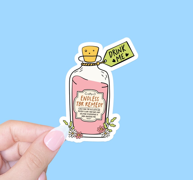 K&ouml;nnte beinhalten: Eine rosa Zaubertrankflasche mit einem Etikett, auf dem "Endless TBR Remedy" steht, und einem Anh&auml;nger mit der Aufschrift "Drink Me". Die Flasche ist von kleinen wei&szlig;en Blumen umgeben.