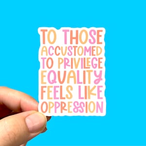 Puede incluir: Una pegatina blanca con un dise&ntilde;o de texto rosa, naranja y amarillo que dice "Aquellos que est&aacute;n acostumbrados a los privilegios, la igualdad se siente como opresi&oacute;n."