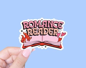 May include: A pink and red sticker with the text "Romance Reader" in a comic book style font. The sticker features a pink open book with flames coming from the pages and hearts around it.