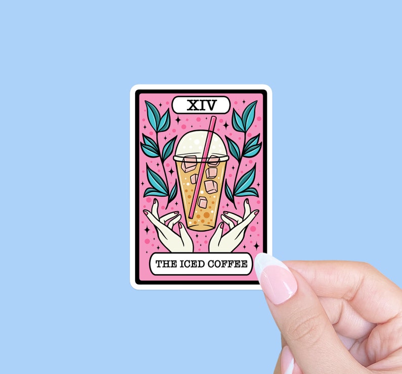 May include: A sticker featuring a tarot card design with a pink background. The card depicts an iced coffee in a clear cup with a pink straw, surrounded by hands and leaves. The text "XIV" and "THE ICED COFFEE" are also present.