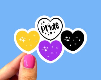 May include: Three heart-shaped stickers with glitter accents. The top sticker is white with black text that reads "pride". The left sticker is yellow with gold glitter. The right sticker is black with white glitter. The bottom sticker is purple with white glitter.