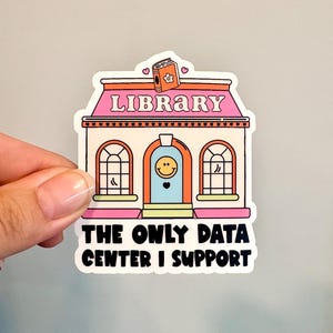 May include: A die-cut sticker featuring a cartoon library building with a pink roof, a light blue door with a smiley face, and an orange book icon on top. The text reads LIBRARY and THE ONLY DATA CENTER I SUPPORT in bold black lettering.
