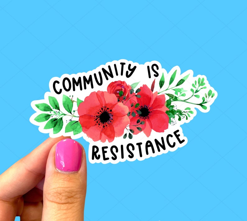 K&ouml;nnte beinhalten: Ein wei&szlig;er Aufkleber mit roten Aquarellblumen und dem Text "Community is Resistance".
