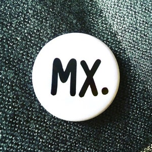 May include: A white button with the letters "MX." in bold black font. The button is circular and set against a textured, dark green background. The design is simple and modern.