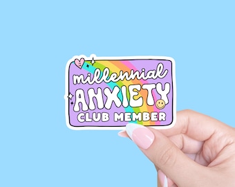 May include: A purple sticker with a rainbow arc and the text "millennial anxiety club member" in a colourful, bubbly font. A small heart and a star are on the sticker.