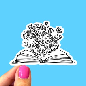 Puede incluir: Un dibujo en blanco y negro de un libro abierto con un ramo de flores que crece de &eacute;l. Las flores est&aacute;n estilizadas y tienen formas simples.