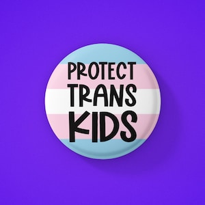 May include: A round button with the transgender pride flag colors and the text "PROTECT TRANS KIDS" in black.