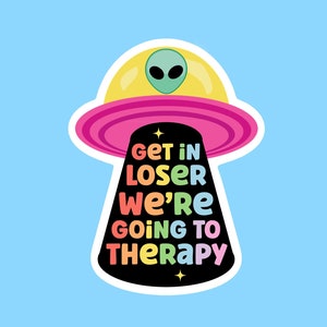 May include: A sticker featuring a cartoon UFO with a green alien and the text "GET IN LOSER WE'RE GOING TO THERAPY" in colourful letters. The UFO is yellow and pink, set against a light blue background.