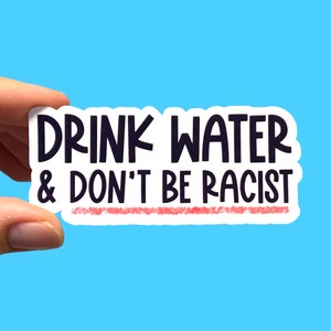 May include: White sticker with black text that reads "Drink Water & Don't Be Racist" with a red line underneath the text.