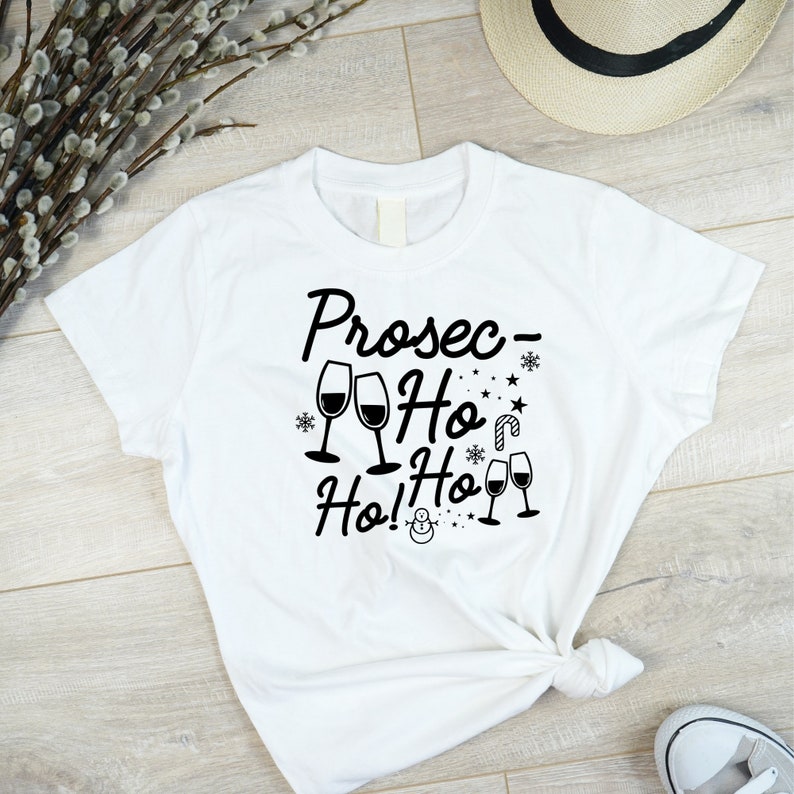 May include: White t-shirt with black text that reads "Prosec-Ho Ho Ho!" with a snowman and wine glasses.