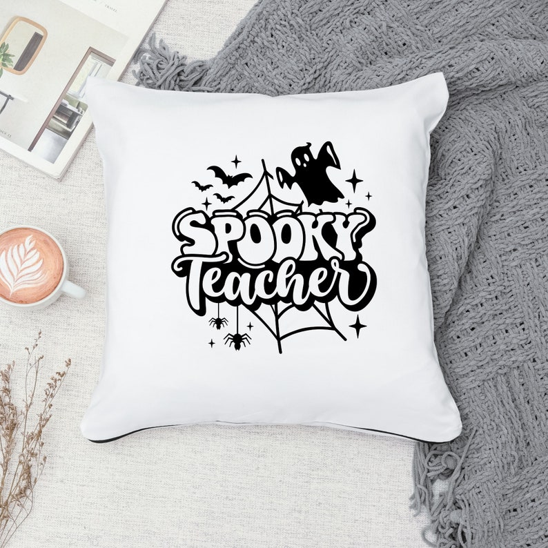 Pu&ograve; includere: Cuscino bianco con testo nero che recita "Spooky Teacher" con un fantasma, pipistrelli, ragni e una ragnatela.