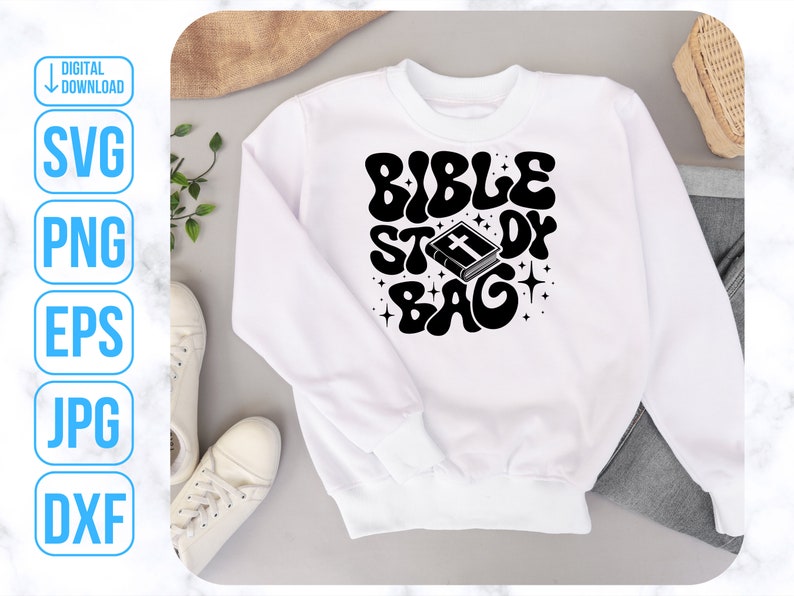 Op de afbeelding: Wit sweatshirt met zwarte tekst die "Bible Study Bag" in een retro-lettertype luidt. Een zwart-witte illustratie van een gesloten boek met een kruis op de omslag bevindt zich boven de tekst.