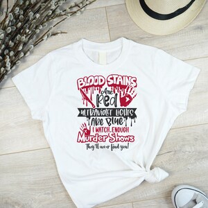 May include: White t-shirt with a red graphic that says "Blood Stains Are Red Ultraviolet Lights Are Blue I Watch Enough Murder Shows They'll Never Find You!"