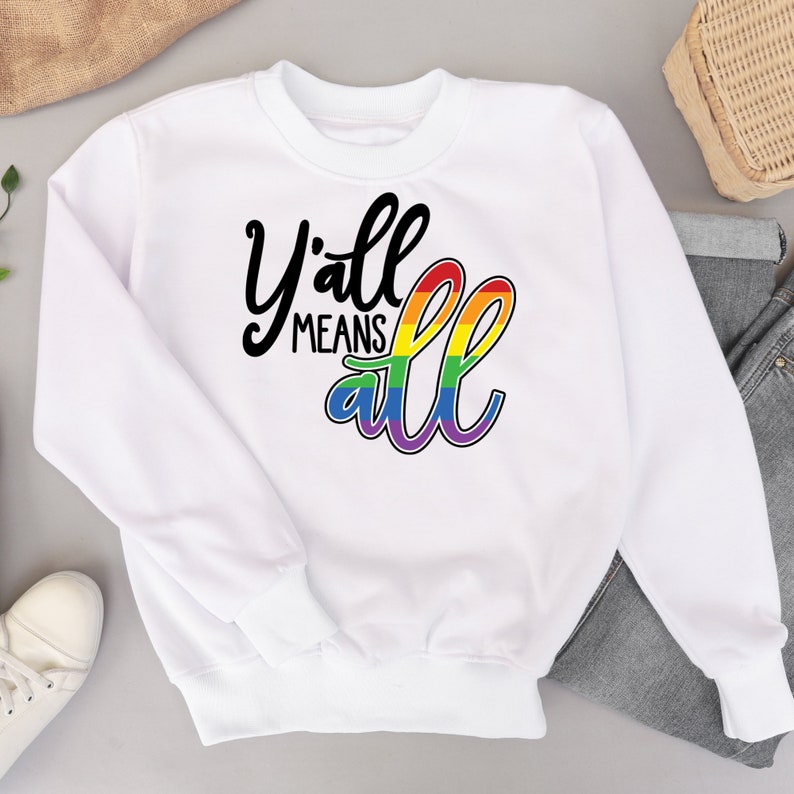 May include: White sweatshirt with the text "Y'all means all" in black lettering with a rainbow arc behind the word "all".