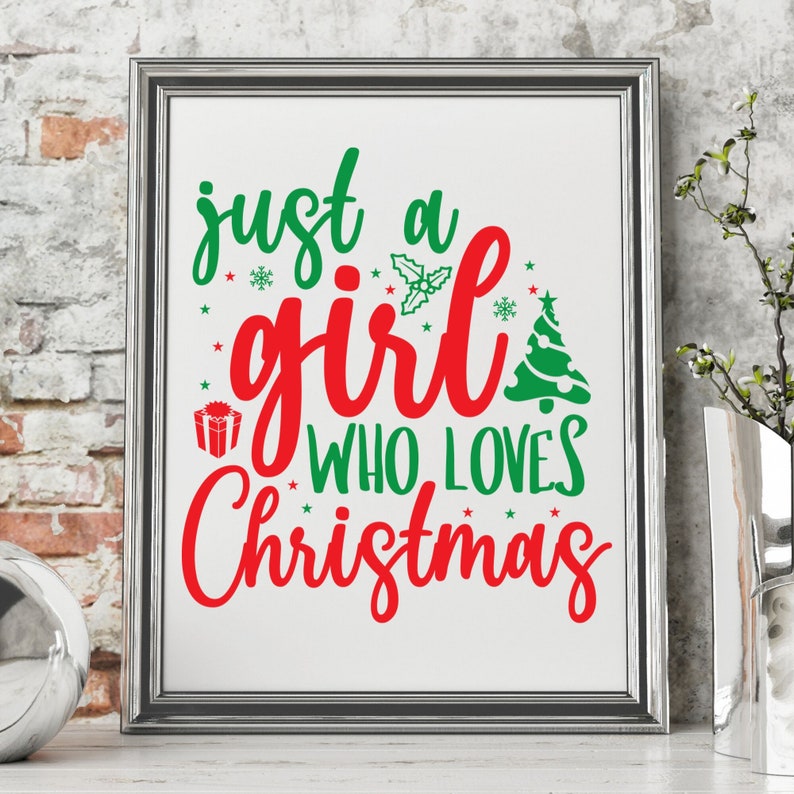 Pu&ograve; includere: Una stampa incorniciata con il testo "just a girl who loves Christmas" in lettere rosse e verdi. Il testo &egrave; circondato da piccole stelle e fiocchi di neve.