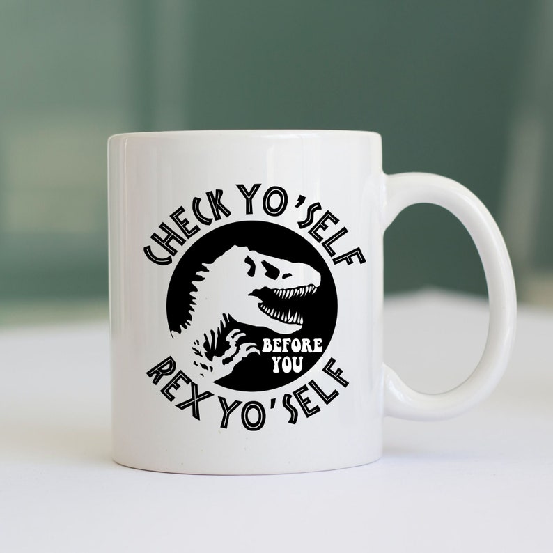 May include: White ceramic coffee mug with a black graphic of a dinosaur with the text "Check Yo'Self Before You Rex Yo'Self"