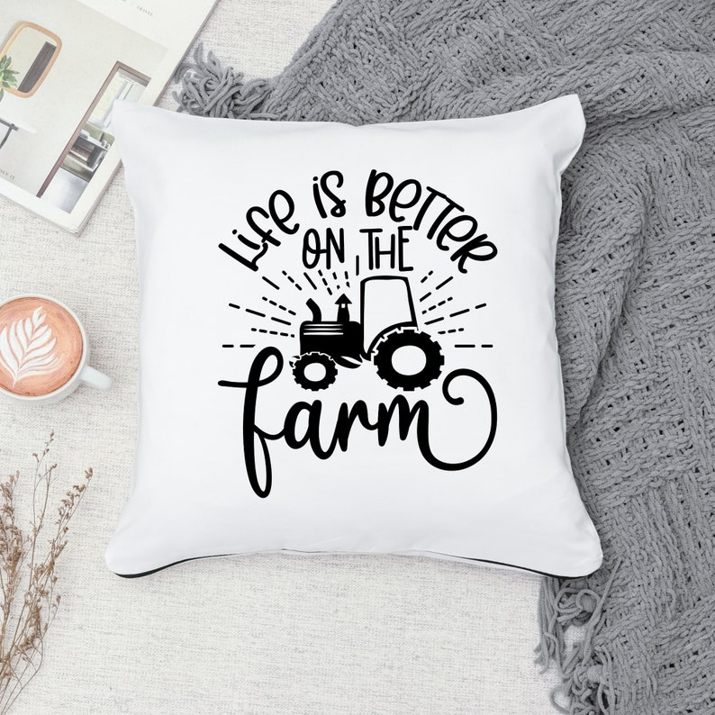 May include: White throw pillow with black text that reads "Life is better on the farm" with a black silhouette of a tractor in the center.