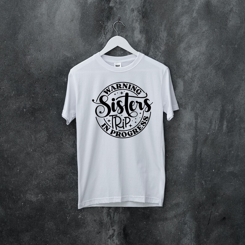 Puede incluir: Camiseta blanca con un gr&aacute;fico circular negro que dice "Warning Sisters Trip in Progress".