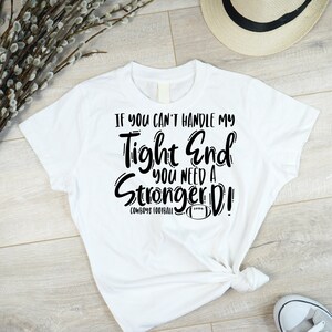 May include: White t-shirt with black text that reads "If you can't handle my tight end you need a stronger D! Cowboys Football".