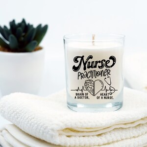 May include: A white candle in a clear glass jar with a black design that says "Nurse Practitioner" with a brain and heart graphic and the text "Brain of a Doctor. Heart of a Nurse."
