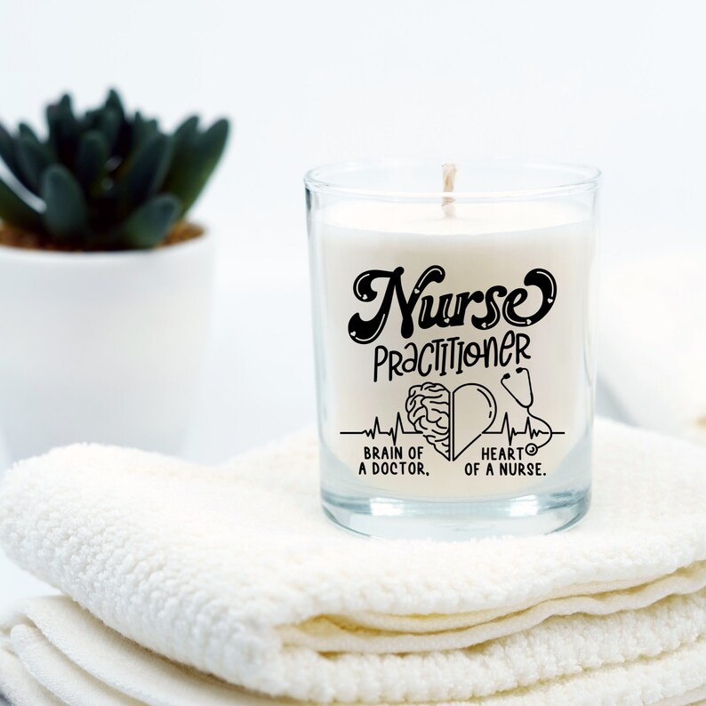 May include: A white candle in a clear glass jar with a black design that says "Nurse Practitioner" with a brain and heart graphic and the text "Brain of a Doctor. Heart of a Nurse."