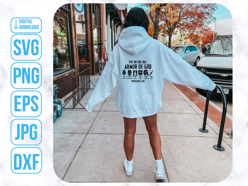 Puede incluir: Una sudadera con capucha blanca con el texto "Ponte la armadura completa de Dios" y un gr&aacute;fico de la armadura de Dios. El texto "Efesios 6:10-18" tambi&eacute;n est&aacute; incluido en la sudadera.