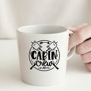May include: White ceramic mug with a black graphic of two crossed marshmallows and the text "CABIN Crew" in a circle.