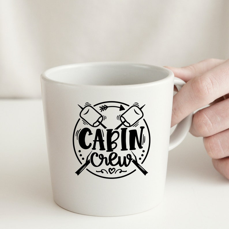 May include: White ceramic mug with a black graphic of two crossed marshmallows and the text "CABIN Crew" in a circle.