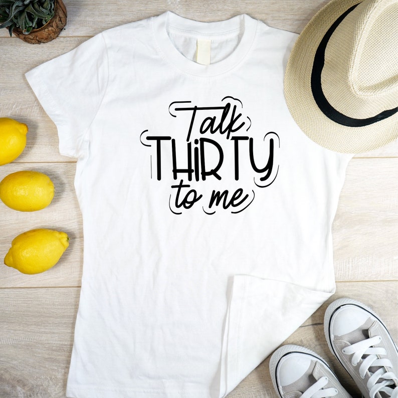 May include: White t-shirt with black text that reads "Talk Thirty to Me".