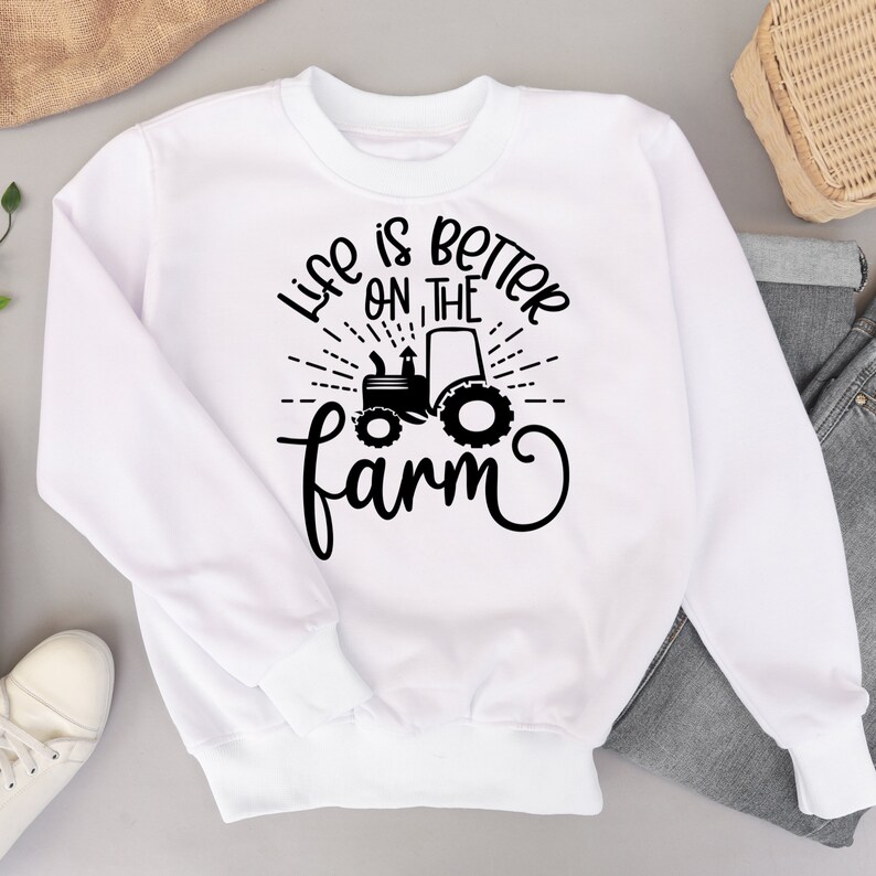 May include: White sweatshirt with black text that reads "Life is better on the farm" with a silhouette of a tractor in the middle of the text.