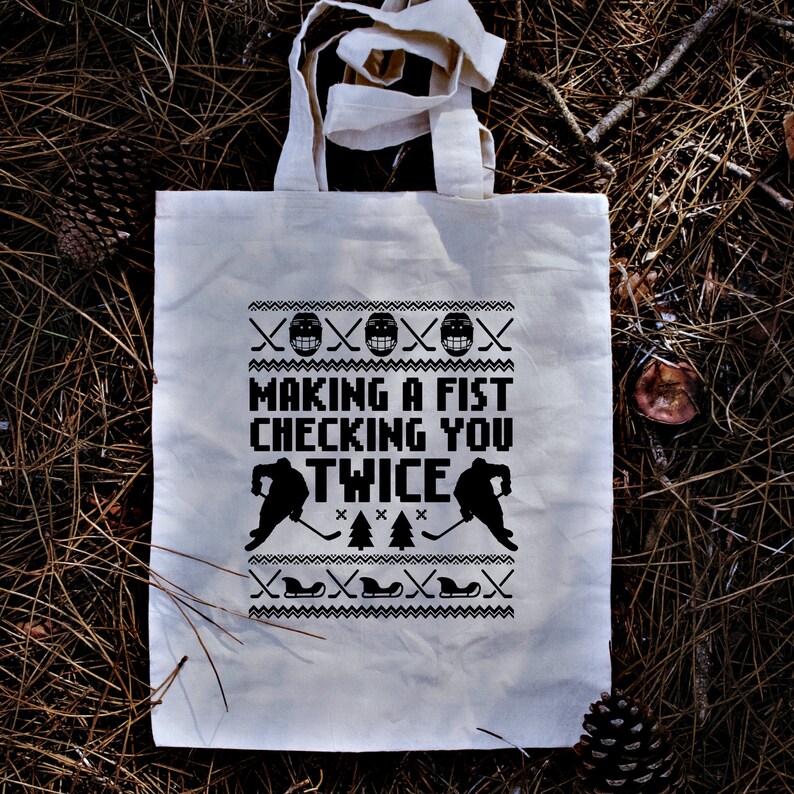 Puede incluir: Bolsa de tela blanca con texto y gr&aacute;ficos negros. El texto dice "Making a fist checking you twice". Los gr&aacute;ficos son jugadores de hockey y palos.