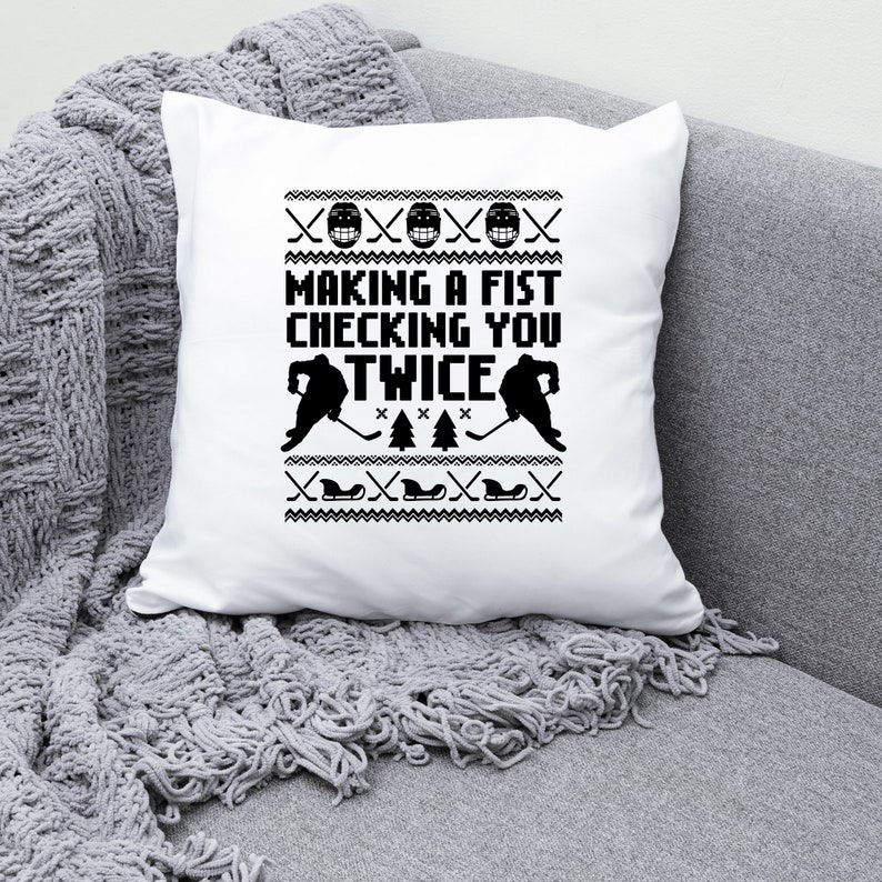 Puede incluir: Coj&iacute;n blanco con un dise&ntilde;o de hockey en blanco y negro. El texto en el coj&iacute;n dice "Making a fist checking you twice".