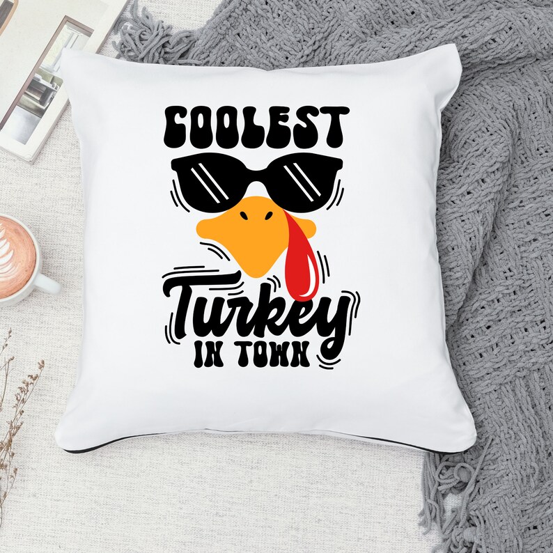 May include: White throw pillow with a black and yellow turkey design. The turkey is wearing sunglasses and the text "Coolest Turkey in Town" is printed below the turkey.