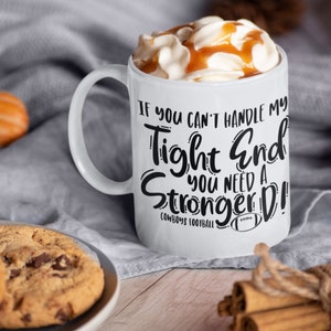 May include: White ceramic mug with a black graphic that reads "If you can't handle my tight end you need a stronger D!" with the text "Cowboys Football" below. The mug is filled with coffee and topped with whipped cream and caramel.