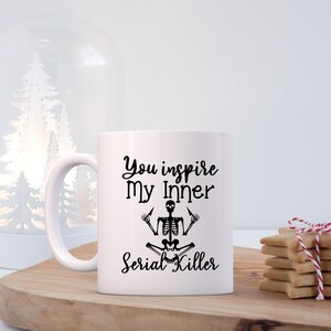 May include: White ceramic mug with black text that reads "You inspire my inner Serial Killer" and a black skeleton illustration in a yoga pose.