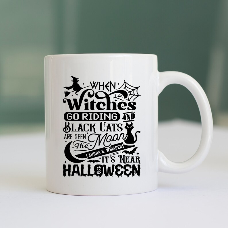 K&ouml;nnte beinhalten: Eine wei&szlig;e Keramik-Kaffeetasse mit einem schwarzen Design, auf dem steht "When Witches Go Riding and Black Cats Are Seen The Moon Laughs & Whispers It's Near Halloween".