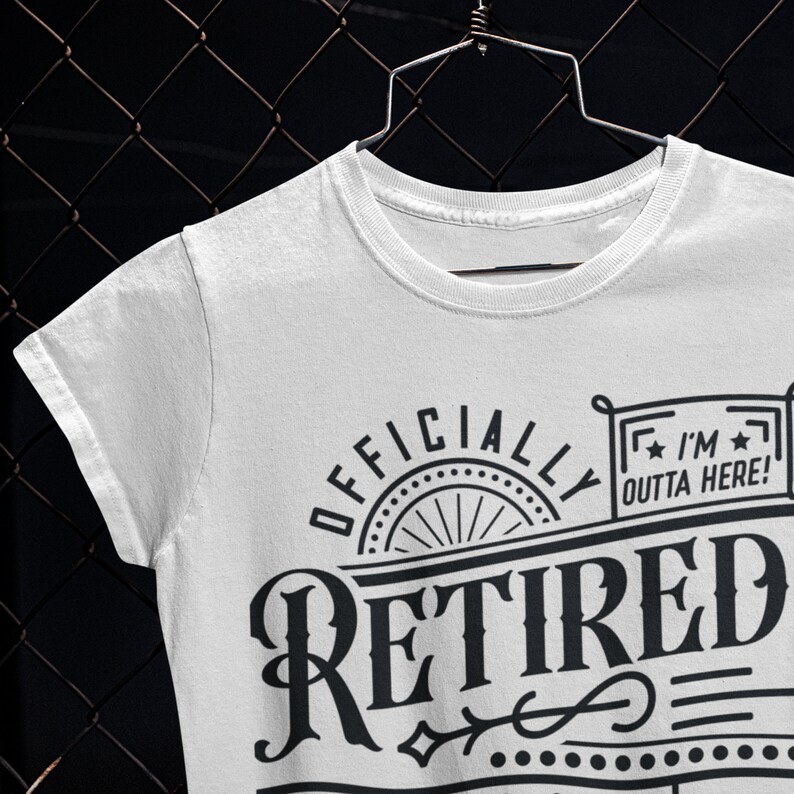 May include: White t-shirt with black text that reads "Officially Retired" with a decorative design and a small rectangle with the text "I'm Outta Here!"