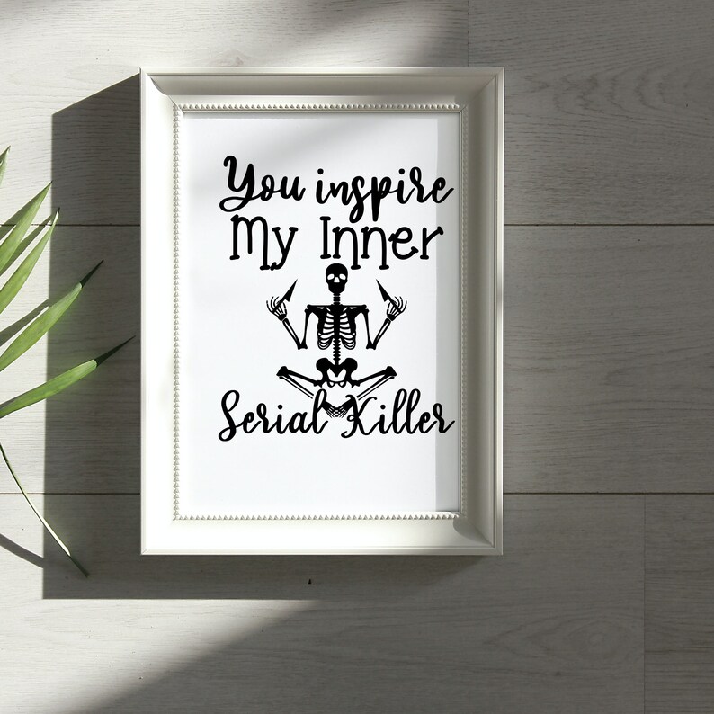 May include: White framed print with black text that reads "You inspire my inner Serial Killer" and a black skeleton illustration sitting in a yoga pose with its middle fingers raised.